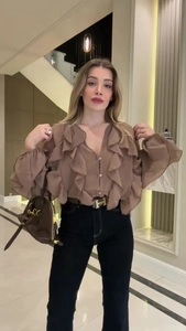 Detail of solid brown long-sleeve blouse with tiered ruffles and V-neckline design