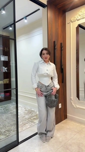 Detail of a white striped lapel shirt paired with wide-leg jeans and woven hobo bag