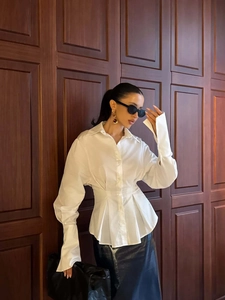 Detail of white tailored shirt featuring cinched waist and wide architectural cuffs