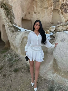 Dettaglio di un vestito bianco a maniche lunghe con orlo a balze e colletto su una modella