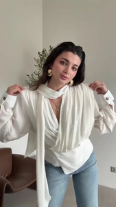 Close-up of elegant white scarf neck shirt with draped pleated details and long sleeves