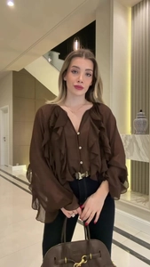 Detailed view of brown long-sleeved ruffle blouse with elegant V-neck and pleated textures