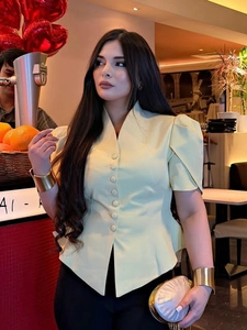 Detail of light yellow V-neck blouse featuring elegant puff sleeves and matching buttons