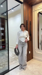 Detailed view of the waist-defining pleats and vertical stripes on a white women's shirt