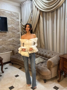 Detail of off-shoulder long sleeve top with button decor and layered ruffle cuffs