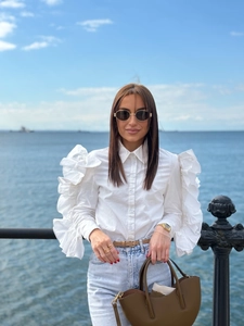 Outdoor street style view of white ruffle-sleeved shirt with crisp cotton fabric texture