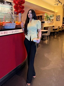 Detail of pale yellow V-neck button-down shirt paired with high-waist black trousers