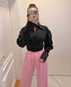 Detail of black pleated lantern sleeve shirt paired with pink straight trousers