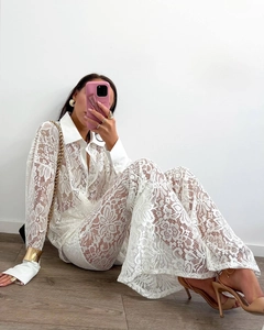 Detail of white floral crochet lace texture on elegant long-sleeve shirt and trousers