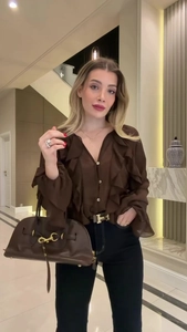 Detail of ruffle sleeve texture and brown leather handbag with gold metal clasp