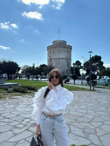 Close-up of white long sleeve blouse featuring dramatic layered ruffle sleeves and cotton fabric