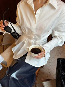 Detail of white long sleeve pleated waist shirt with a cinched silhouette design