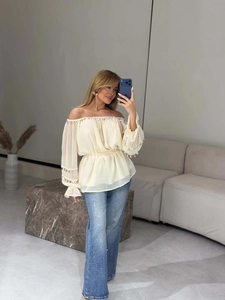 Detail of off-white off-shoulder blouse with sequin trim and ruffled sleeves design