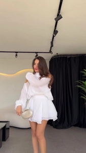 Chic two-piece white off-shoulder top and pleated mini skirt set with gold clutch