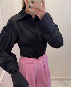 Detail of black lapel shirt showing single-breasted buttons and pleated lantern sleeves