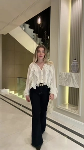 Detail of white ruffle chiffon blouse with elegant pleated edge and front button design