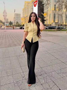 Detailed view of the yellow V-neck short sleeve shirt and high waist black flared trousers