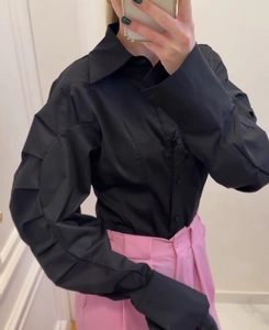 Detail of black pleated puff sleeves on long-sleeve lapel shirt for women