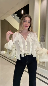 Detailed close-up of white ruffle blouse with V-neckline and elegant long sleeves for women