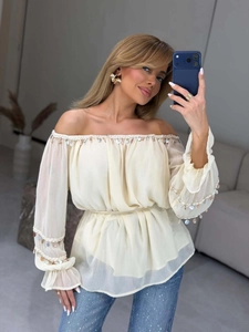 Detail of off-white off-shoulder chiffon blouse with shell beads and waist belt