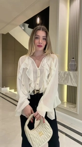 Detail of white V-neck chiffon shirt with ruffles and a classic gold buckle belt