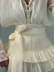 Dettaglio del corpetto in pizzo crema con bottoni di perle e cintura in chiffon in vita