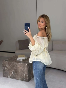 Detail of off-shoulder chiffon blouse with sequins and rhinestone denim jeans