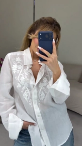 Close-up of elegant floral embroidery and button-down detail on a white casual shirt