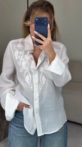 Detail of white embroidered flower shirt with elegant vine patterns and lapel collar design