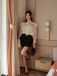 Detail of a beige chiffon shirt with bow tie neckline and elegant ruffled layers for women