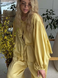 Detail of ginger silk pajama set featuring bow-tie waist and lantern sleeve texture