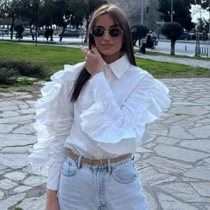 White long-sleeve blouse featuring elegant ruffled sleeves and a classic collar design