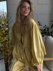 Detailed view of yellow satin two-piece set featuring lantern sleeves and tie-up design