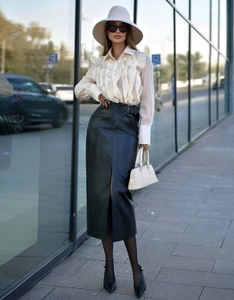 Detailed view of the ruffle trim on a chic white long sleeve shirt and faux leather skirt