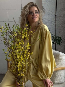 Detail of yellow silk long sleeve blouse with elegant bow tie neck and draped fabric