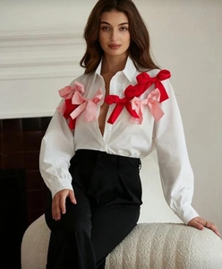 Detail of red and pink satin bows on white long-sleeve blouse with French design