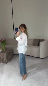 Detail of white button-up shirt paired with blue jeans and gold transparent heels