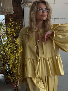 Detail of yellow satin blouse showing three front tie-knots and puffy bubble sleeves