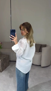 Mirror selfie showing the back view of a white lapel long sleeve shirt with blue jeans