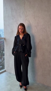 Dettaglio di completo nero in raso a due pezzi con top a V e pantaloni a gamba larga