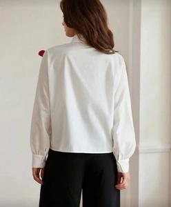 Back view of a white long-sleeved shirt showing minimalist cut and tailored fit for women