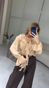 Détail de la blouse à volants, col en V, nœud et poignets élastiques couleur champagne