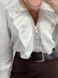 Close-up of white V-neck blouse featuring intricate lace embroidery and ruffled sleeves