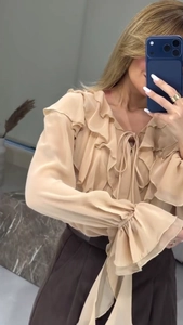 Détails de la blouse en mousseline beige avec volants multicouches et manches trompette