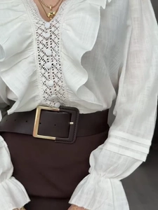 Detail of white ruffle blouse with lace hollow-out and vintage leather belt with gold buckle