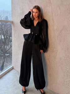 Dettaglio completo di set in raso nero con scollo a V, bottoni dorati e pantaloni ampi