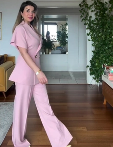 Detail of pink short sleeve waist-fitted blazer with metal buttons and wide-leg pants