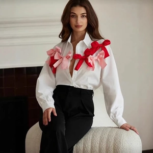 White long-sleeve shirt featuring large 3D red and pink bows on front and shoulders