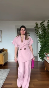 Detail of pink short sleeve blazer with gold buttons and matching wide leg trousers