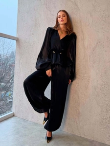 Dettaglio di elegante completo in raso nero con top a portafoglio e pantaloni larghi